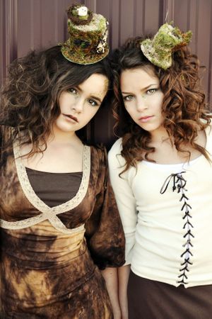 Two models wearing steampunk-inspired outfits and tiny decorative top hats. for Fairie Magazine.