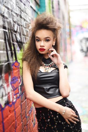 Fashion portrait against graffiti wall wearing black dress and bold red lipstick modeling for Reyna Red.