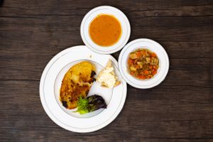 Three plates of Indian curry dishes with naan bread on wooden table. Local Chef