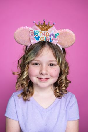 Sparkly pink birthday mouse ears with golden crown on pink background modeling for The Minnie Castle.