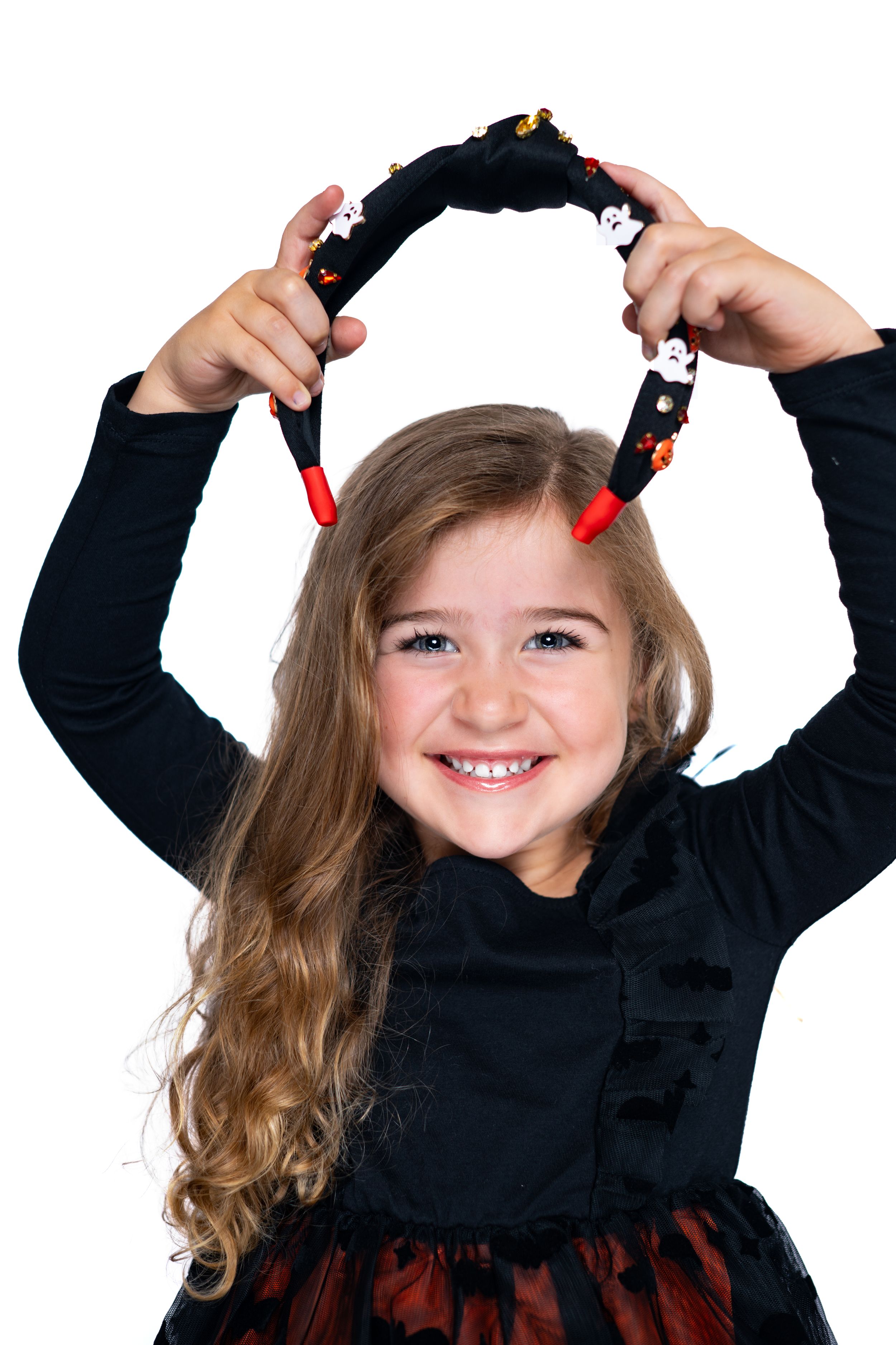Child in black outfit holding decorative holiday headband modeling for Hug A Band.