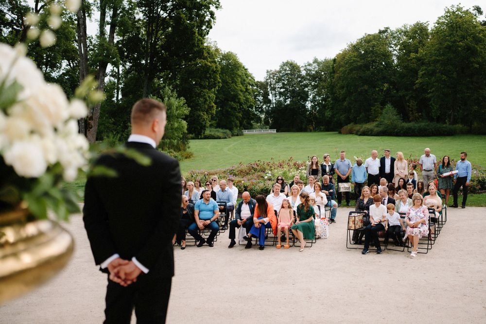 Outdoor wedding ceremony setup with guests seated on a grassy lawn.