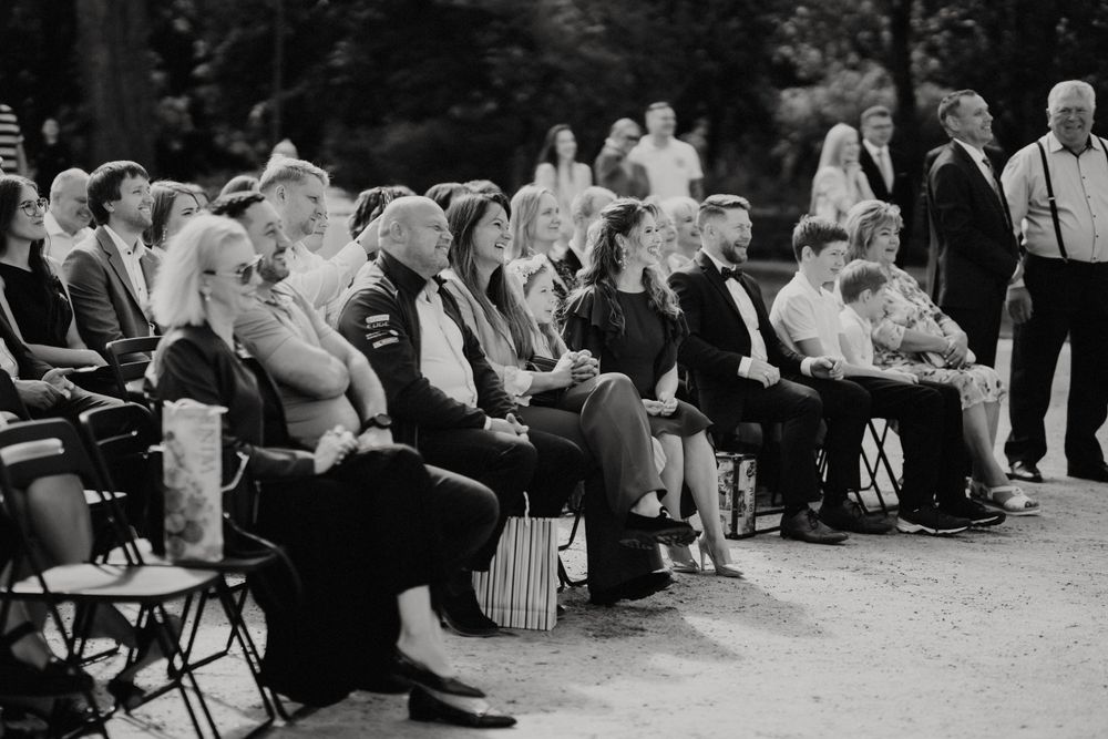 Wedding guests seated in rows during an outdoor ceremony in black and white.