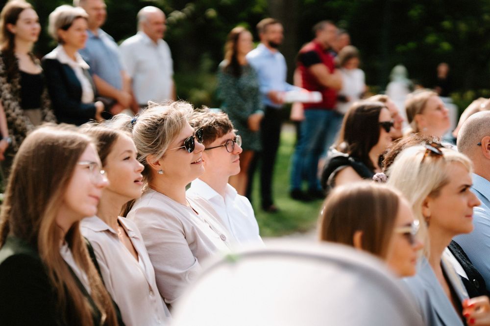 Wedding guests watching ceremony outdoors on a sunny afternoon.