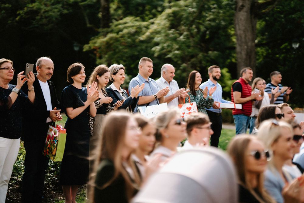 Wedding guests gathered outdoors watching ceremony proceedings in a natural wooded setting.
