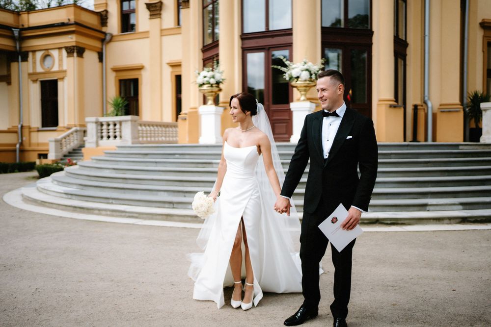 Wedding couple standing on grand stone steps of historic building.