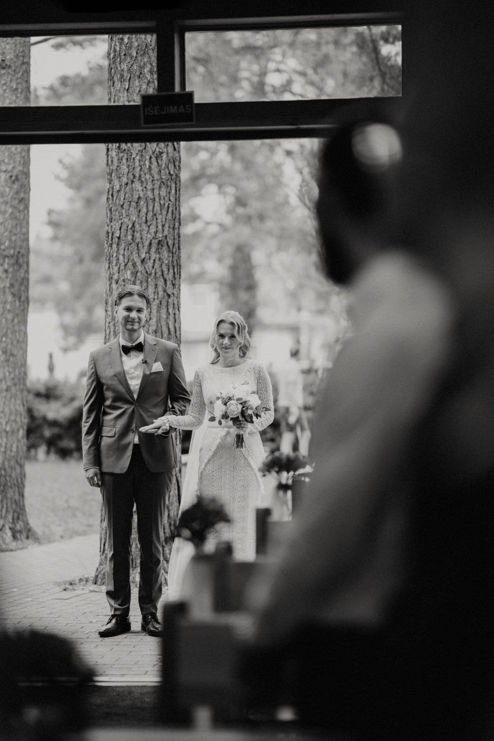 Wedding ceremony in a pine forest with guests gathered along a path.