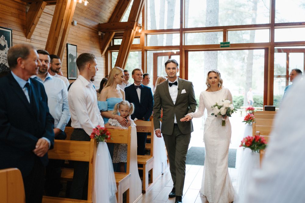 Wedding celebration inside a rustic wooden A-frame venue with large windows.