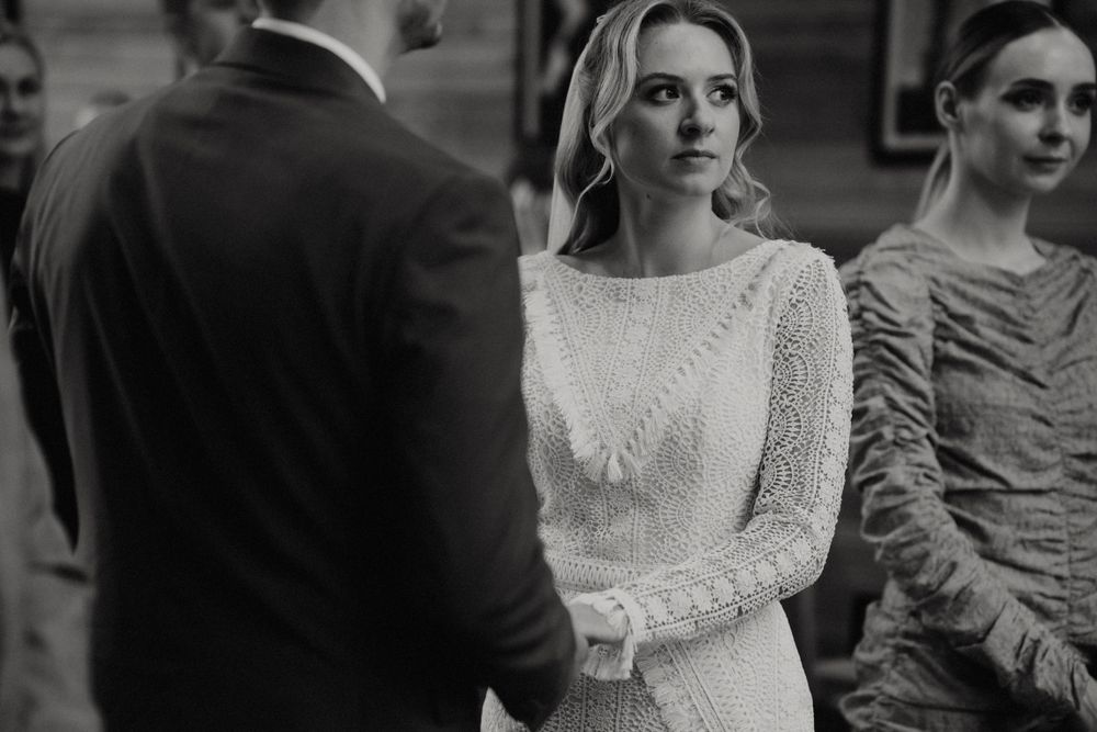 Couple exchanges rings during an intimate wedding ceremony in black and white.