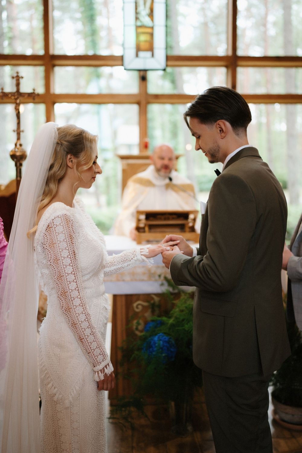 Wedding ceremony in a sunlit chapel with wooden beams and large windows.