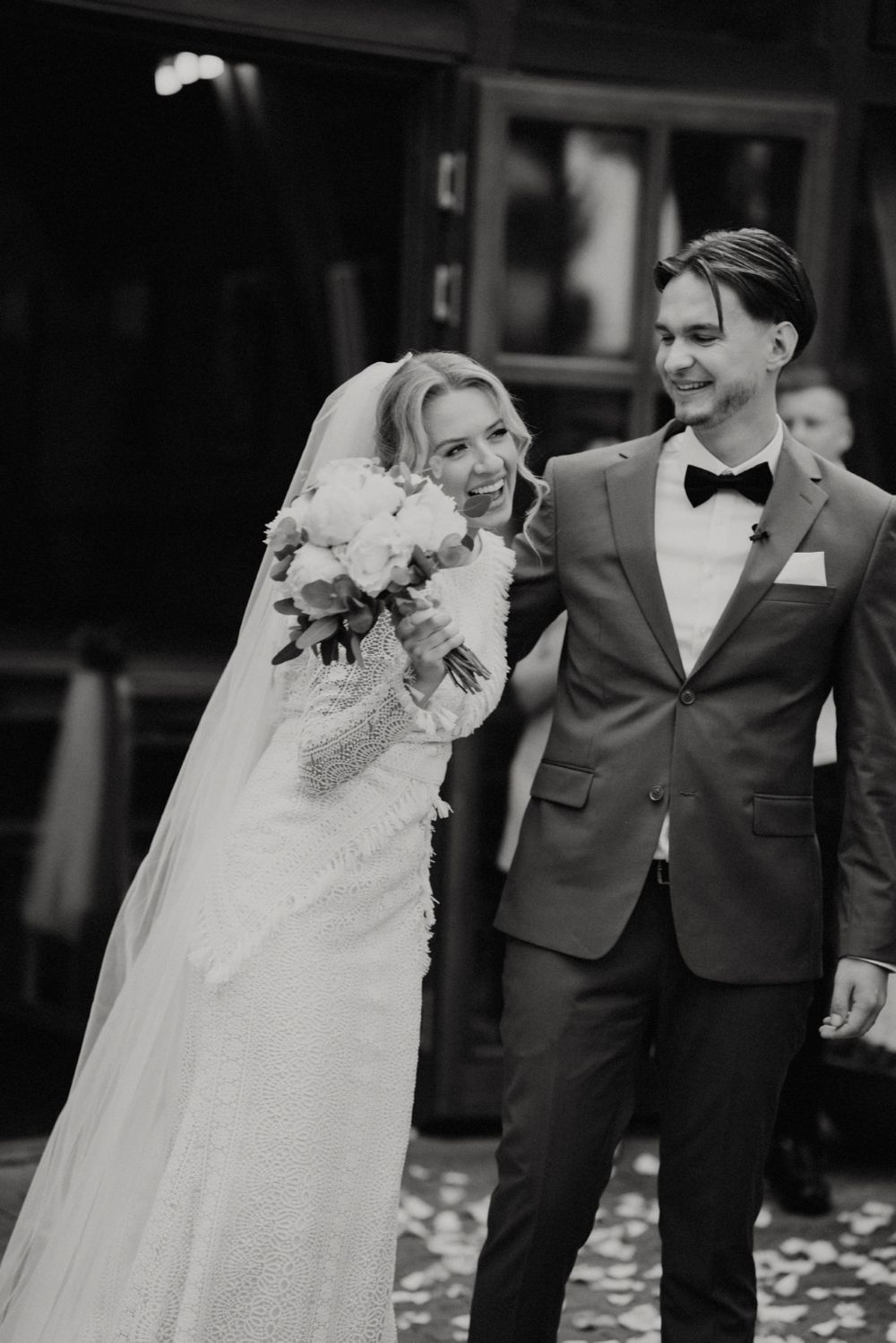 Black and white photo of couple walking together after wedding ceremony.