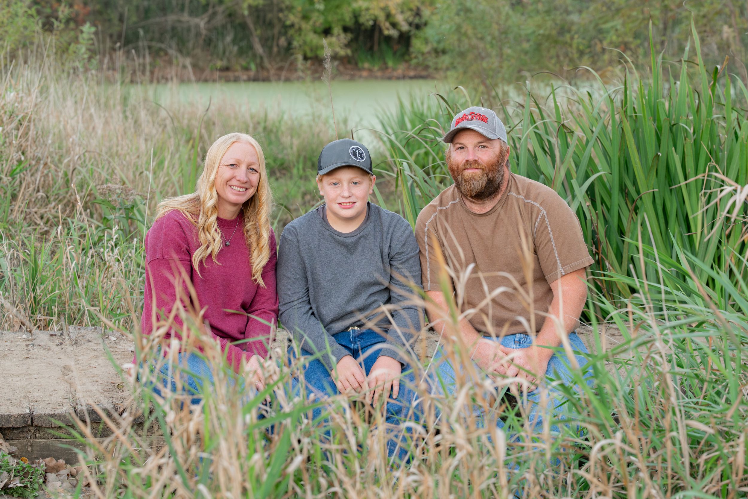 Group portrait in natural setting with tall grass and water in background during autumn season.