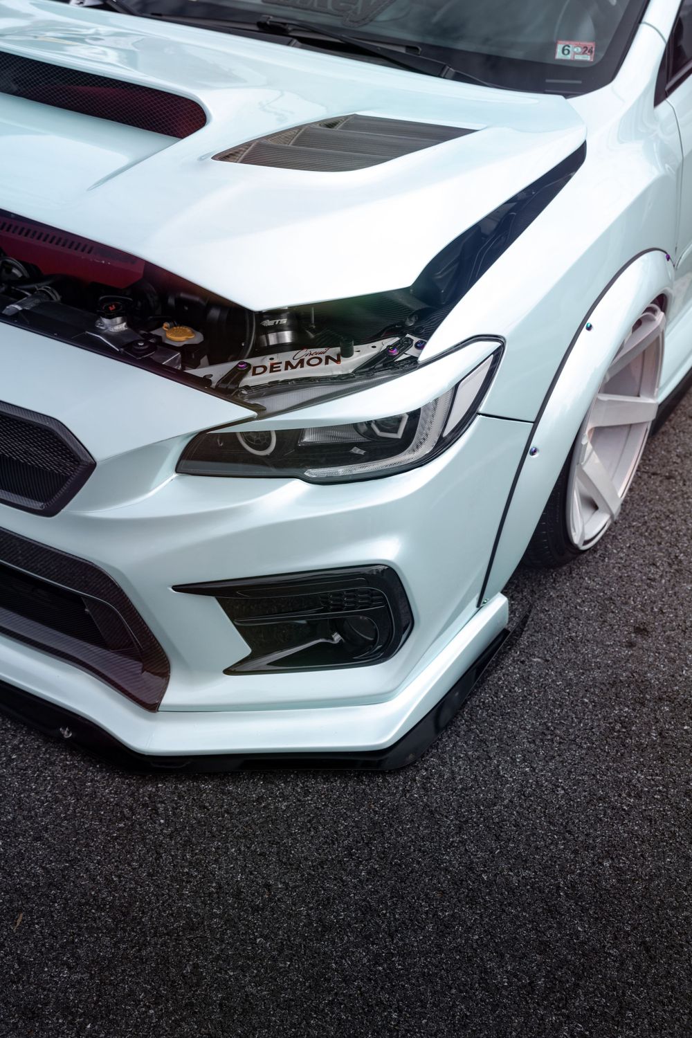 Close-up detail shot of modified white sports car front end with custom bodywork.