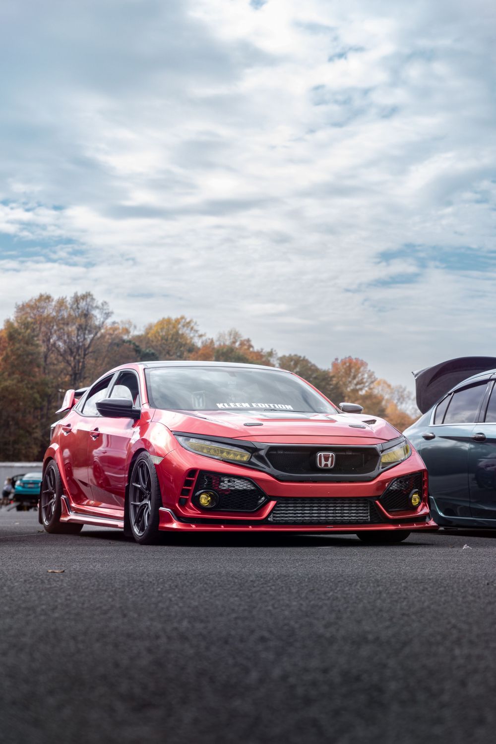 Lowered red Honda Civic Type R with custom body modifications in parking lot.