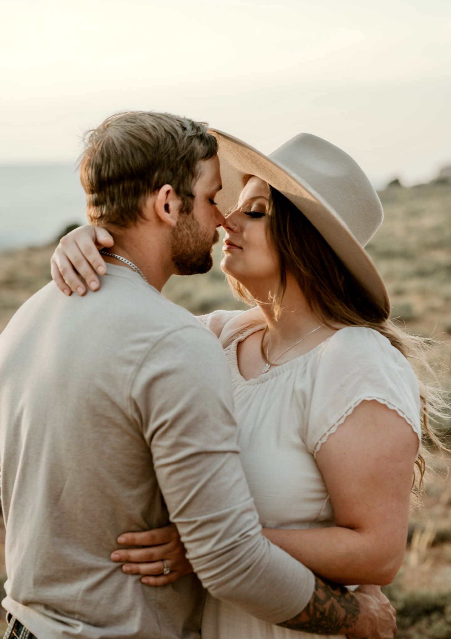 Couple in light colored clothing sharing intimate moments in desert landscape.