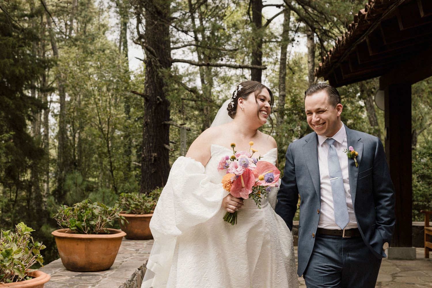 A romantic wedding photoshoot in a lush forest setting with evergreen trees in the background.