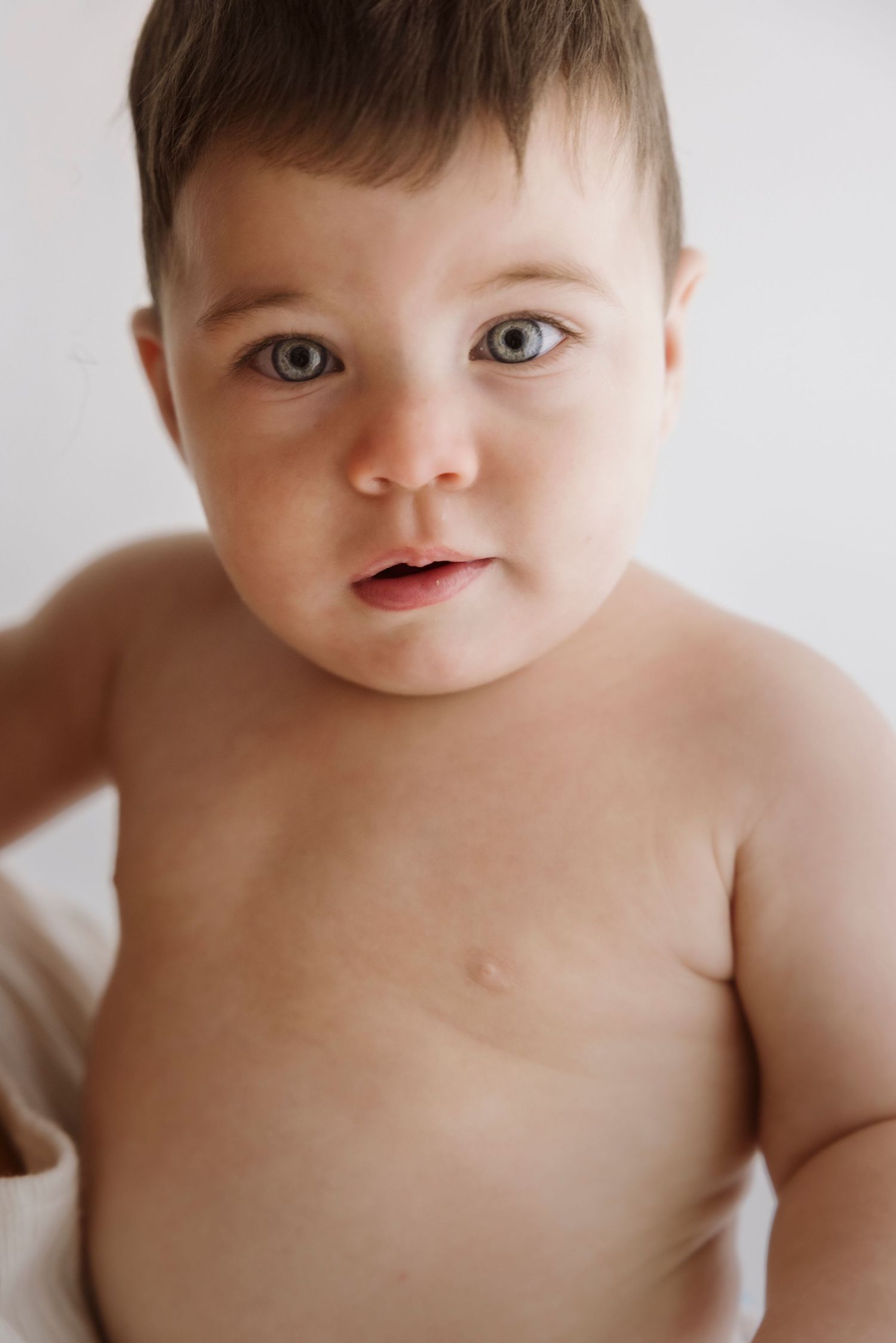 Close-up portraits of a baby with rosy cheeks and bright eyes against a white background.