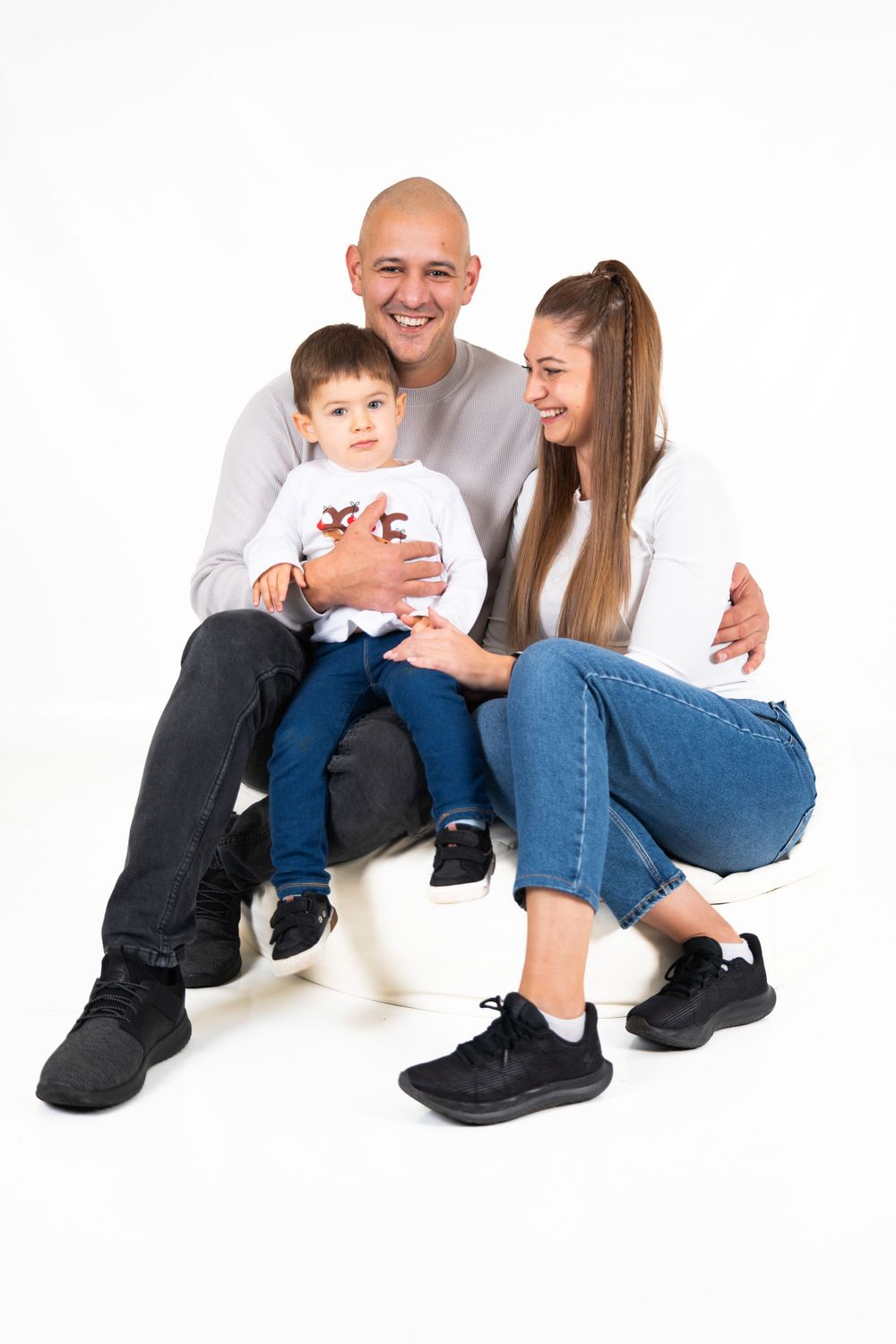Portrait of a family sitting together against white background in casual attire.
