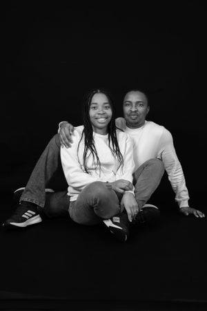 Black and white portrait of a couple in white sweaters sitting close together.