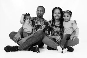 Black and white family portrait with matching outfits against white background.