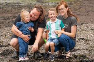 Family sharing a playful moment while crouching together outdoors.