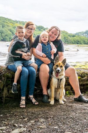 Family seated outdoors with their corgi dog at a waterfront location.