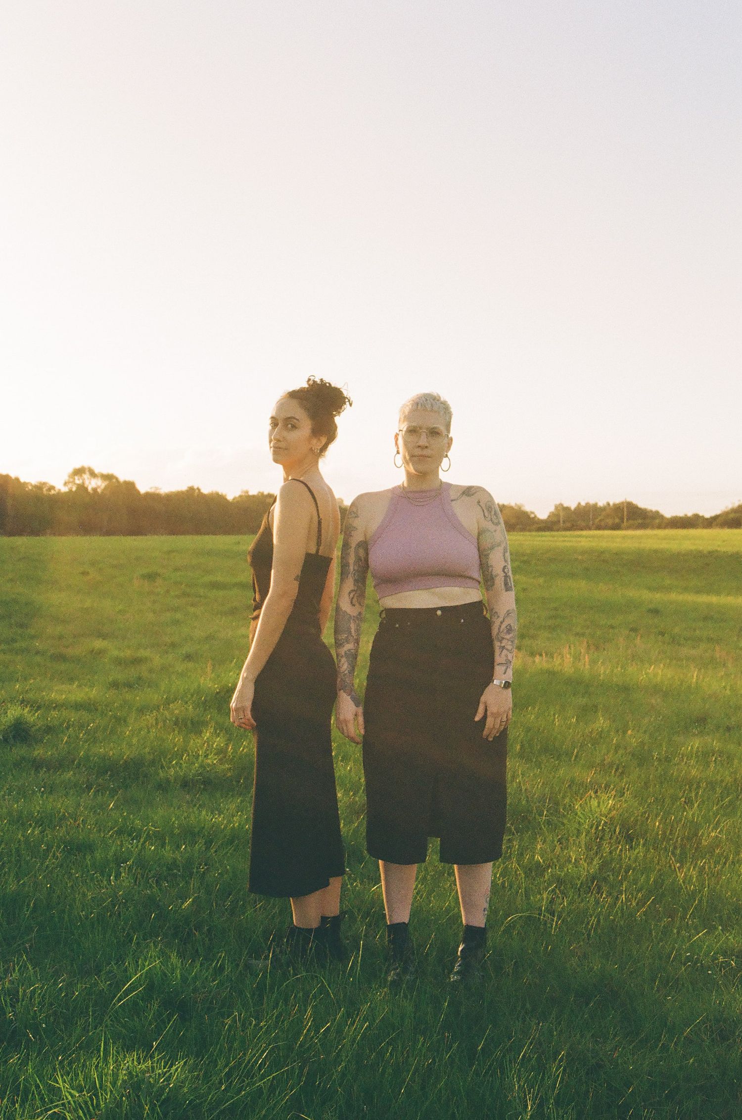 Creative queer love photography in Perth, Lesbian couple photoshoot outdoors, holding each other in a green field.
