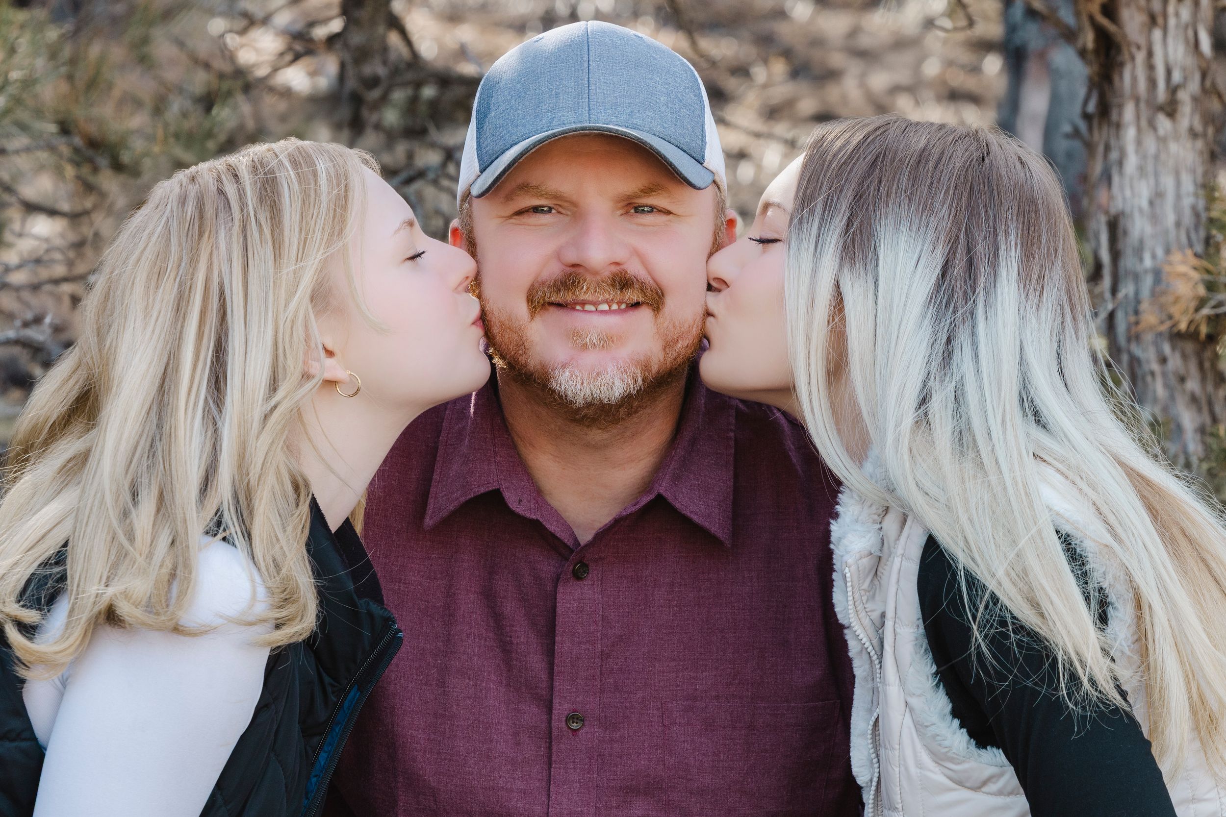 Dad and daughters sharing a cute moment during a family photo session wile recreating a photo.