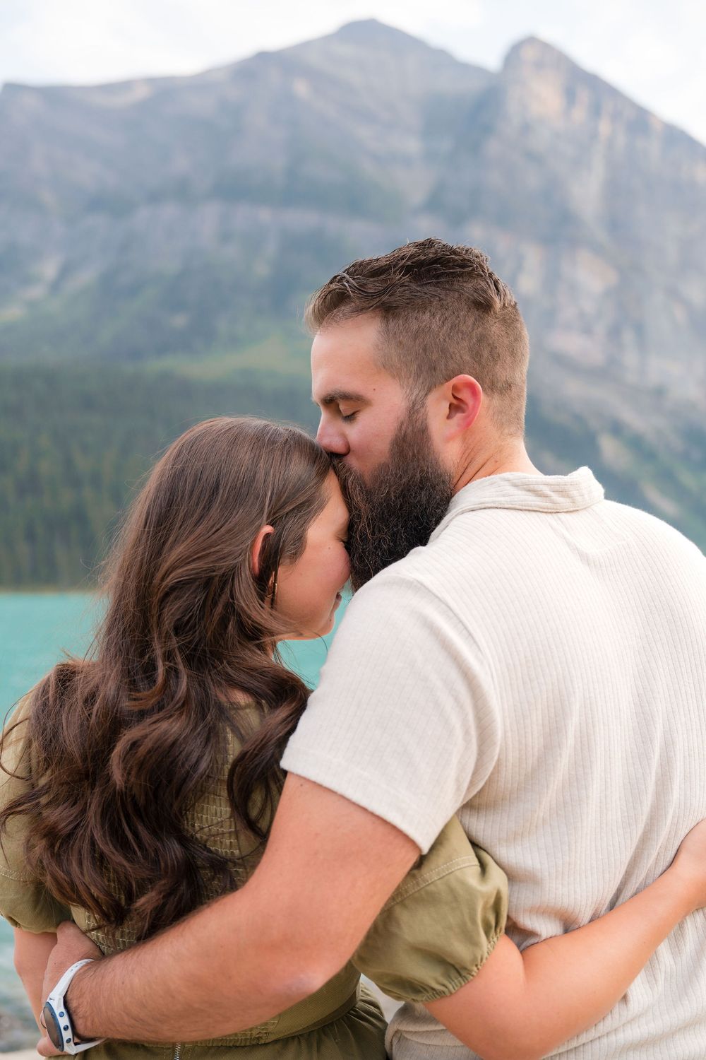 Couple sharing a romantic kiss with turquoise lake and mountain backdrop in Banff National Park.