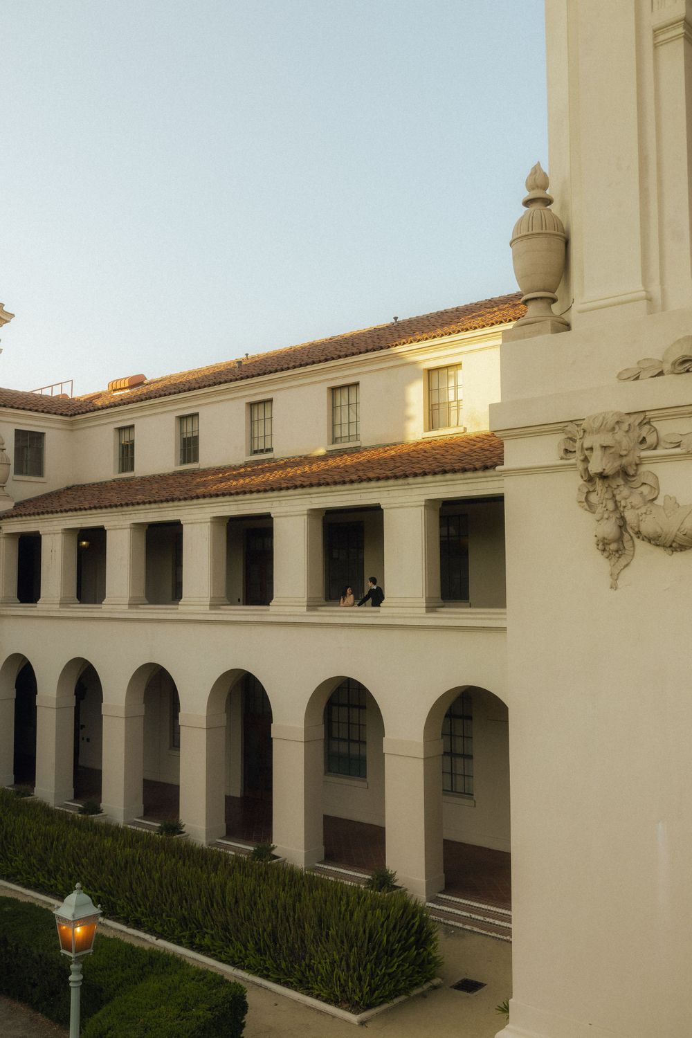 Mediterranean style building with white arched colonnade and terra cotta roof tiles at golden hour.