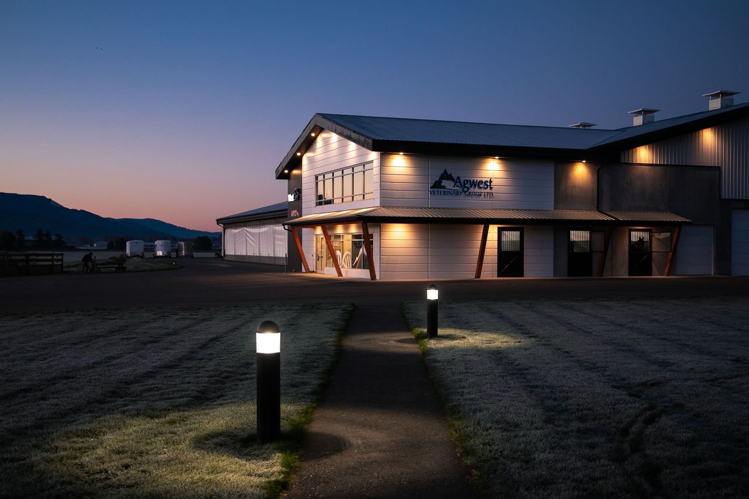 Brewery exterior with warm lighting against a twilight sky and mountains in background.