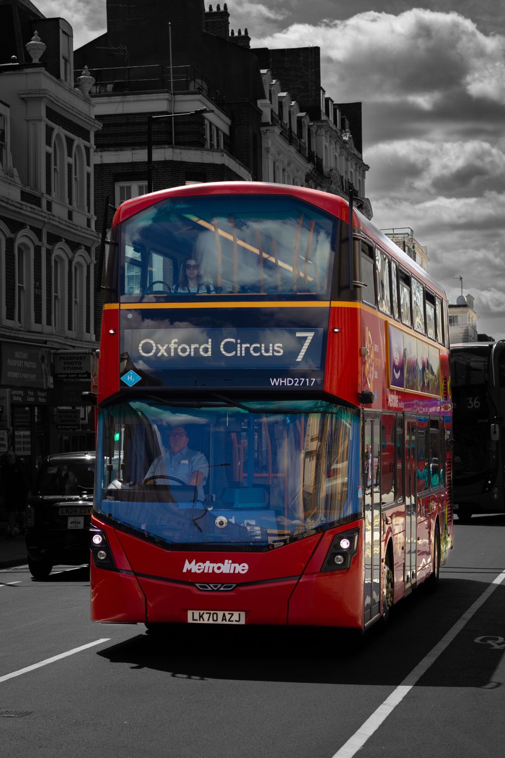 A red double-decker bus numbered 7 heading to Oxford Circus on a London street.