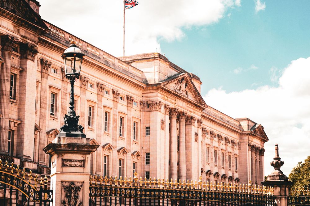 Grand neoclassical architecture of Buckingham Palace under blue sky with white clouds.