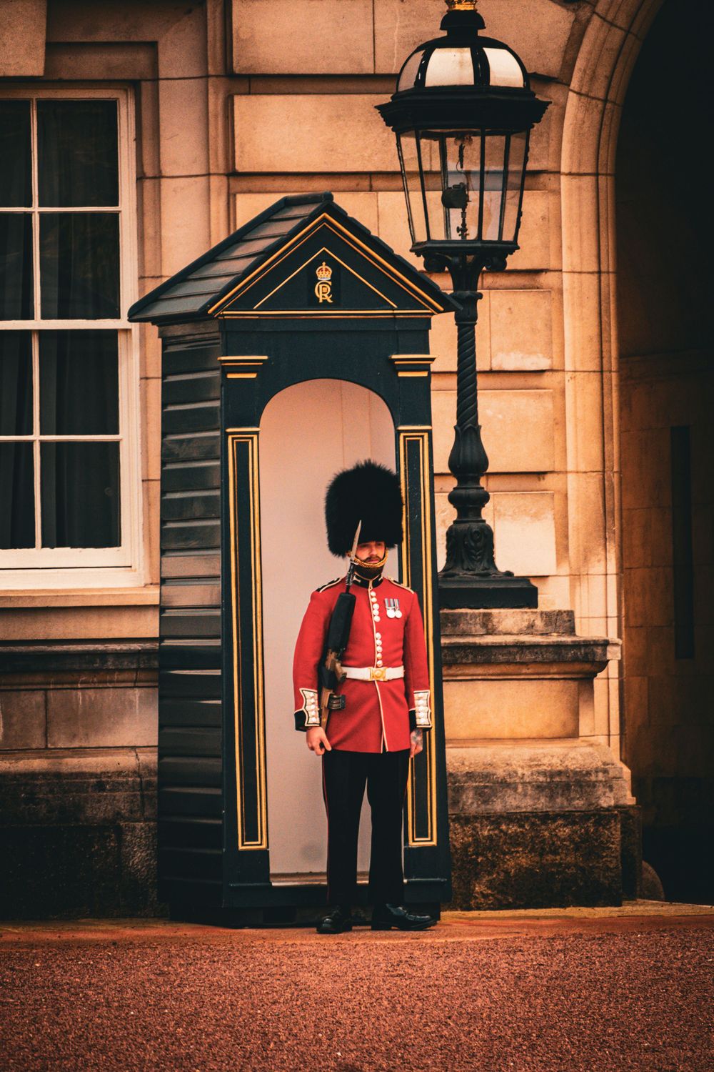 Royal guard sentry box and ornate lamp post against stone palace wall.
