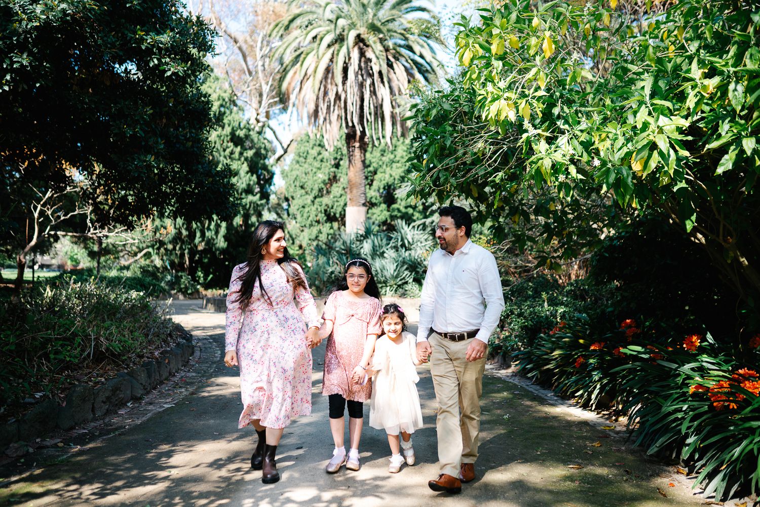 A happy family of 4 in Melbourne's St Kilda Botanical Gardens with lush greeneries as backdrop taken by a Melbourne family photographer.