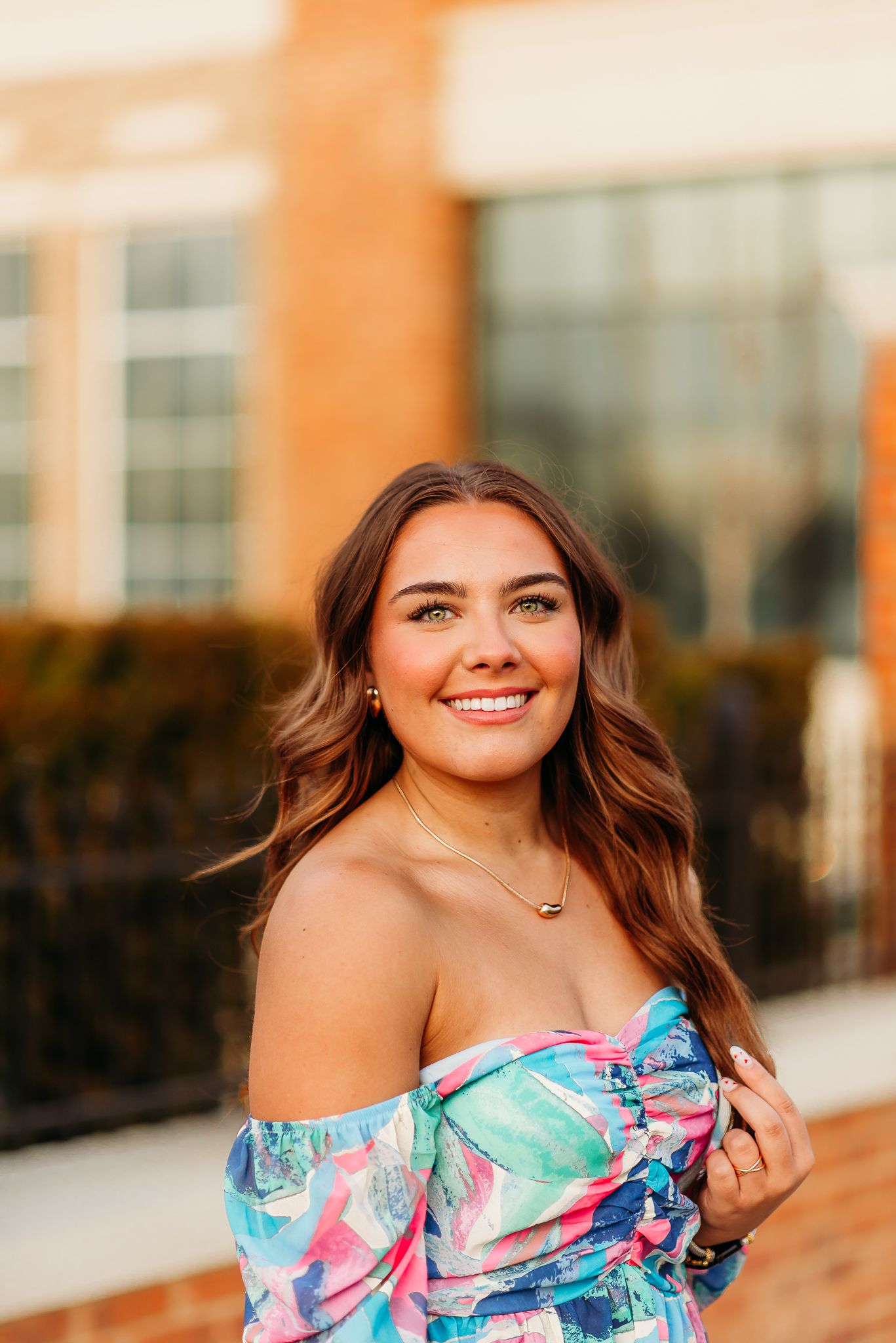 A portrait of someone wearing a colorful floral off-shoulder top during golden hour.