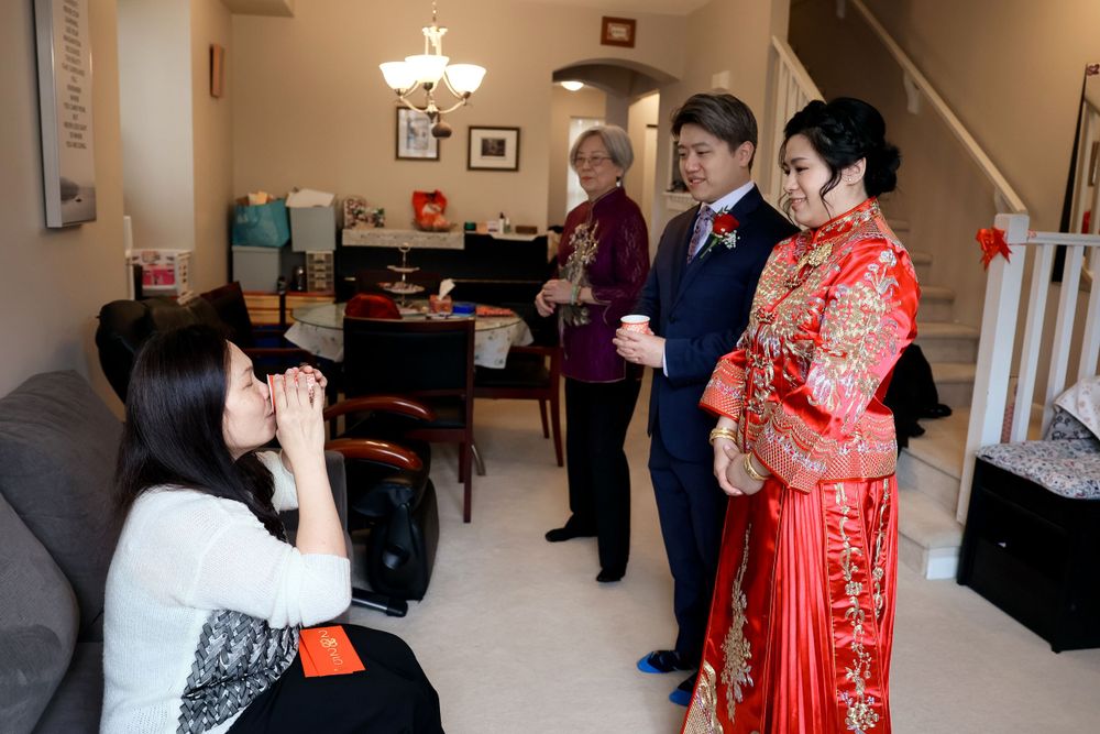 A photographer takes pictures of a couple in traditional Chinese wedding attire during an indoor photo session.