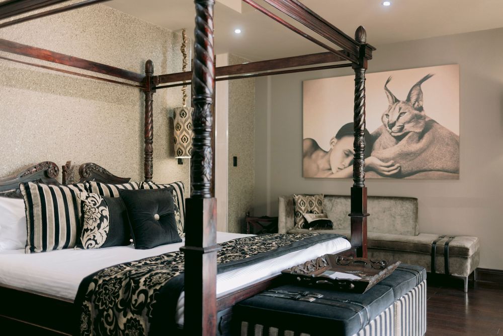 Elegant four-poster bed with black and white decor and animal artwork in a luxury hotel room.