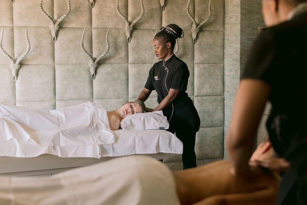 Two therapists perform simultaneous massages in a serene luxury spa treatment room.
