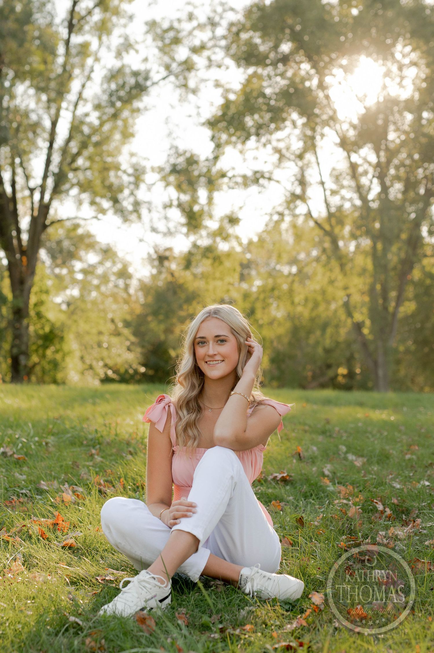 Natural outdoor portrait with casual pose on grass during sunset.