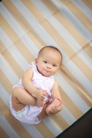 Smiling baby girl lying on a striped mat, captured by Phoebe Lee Photo in Toronto