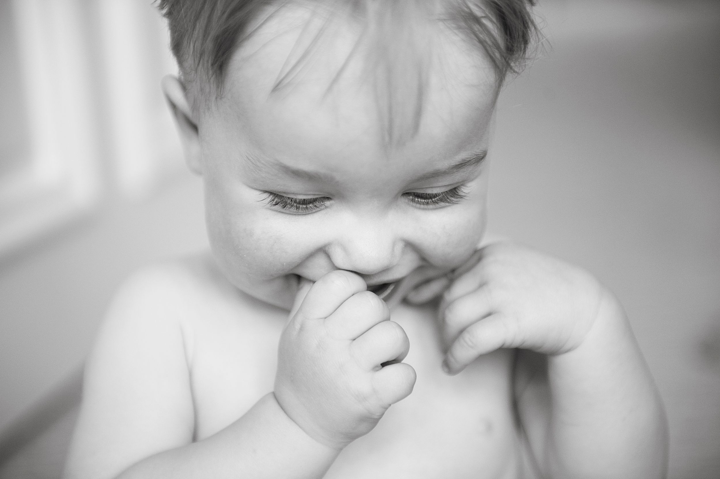Toddler chewing on his fingers in a sweet black-and-white portrait, taken by Phoebe Lee Photo in Toronto