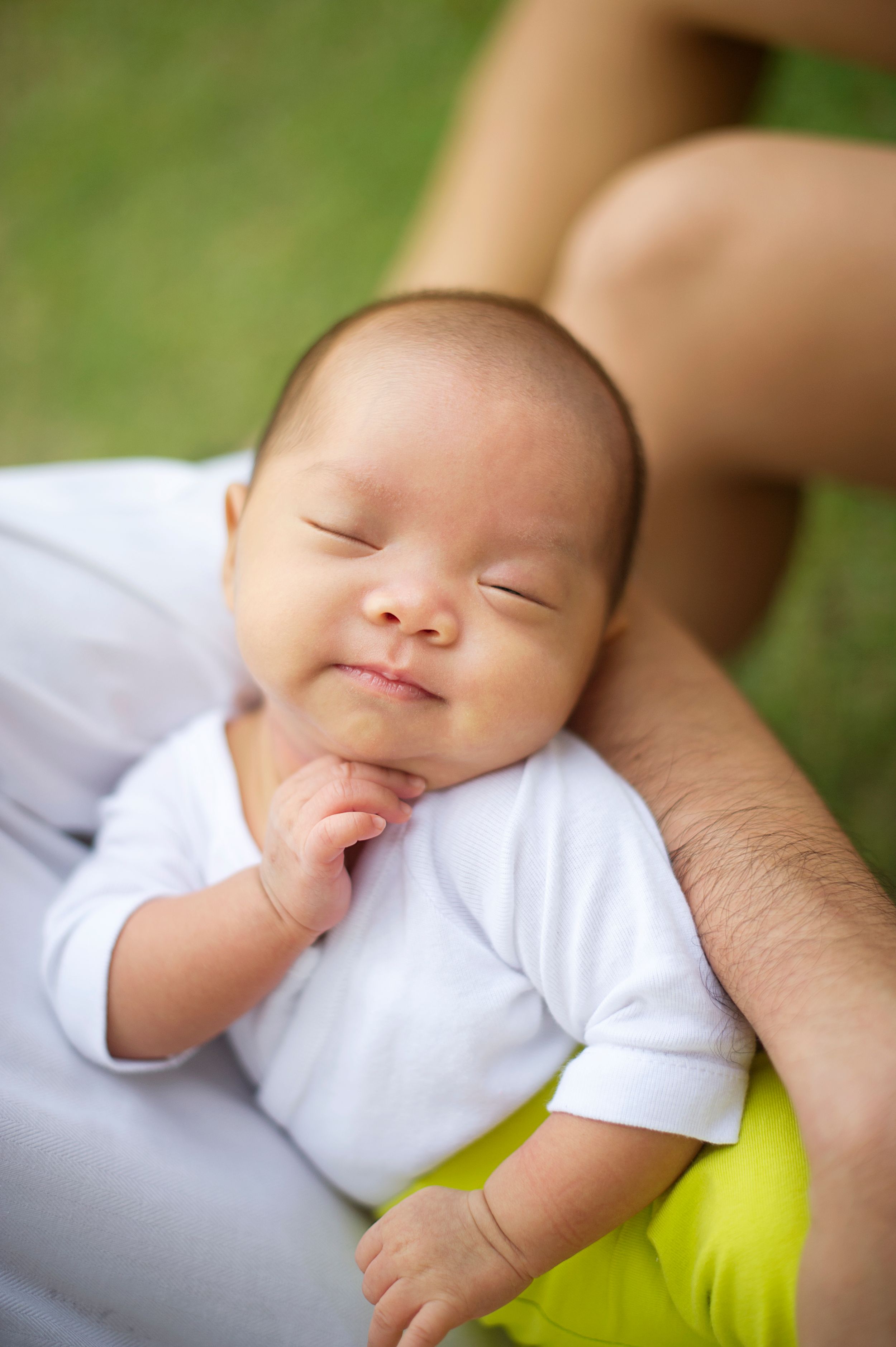 Newborn gazing up while being held in a parent's arms at a Toronto park, photographed by Phoebe Lee Photo