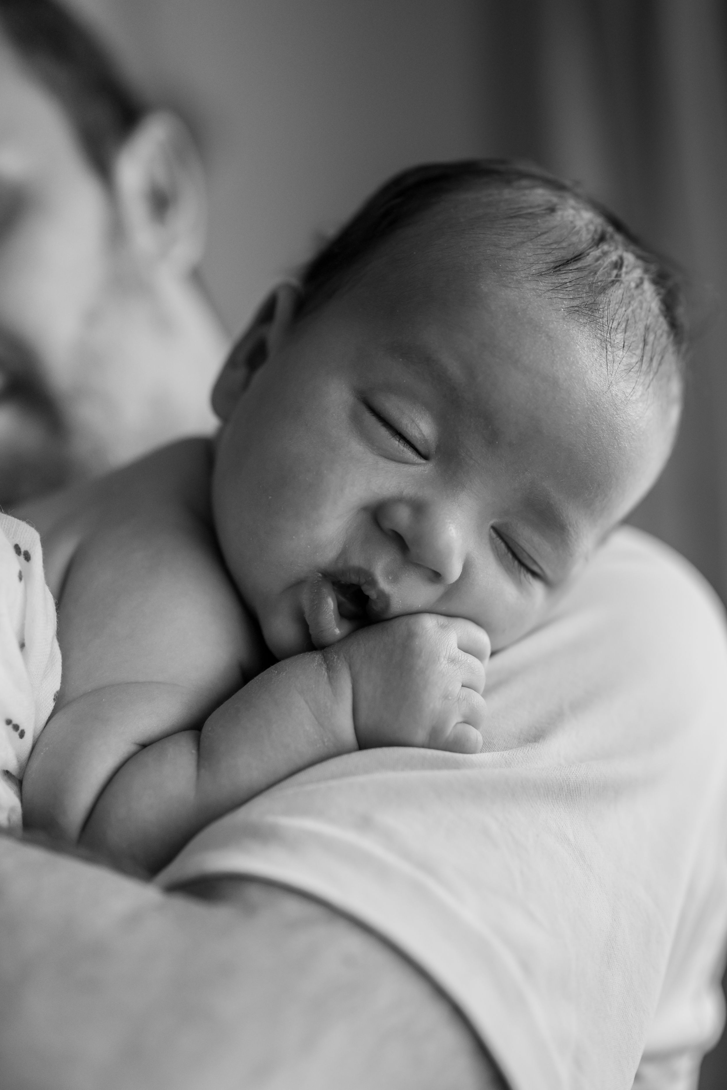 Newborn baby resting on father's shoulder during a Toronto lifestyle photography session by Phoebe Lee Photo.