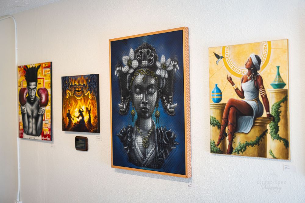 Gallery wall displaying four colorful paintings featuring African-inspired figurative artwork.