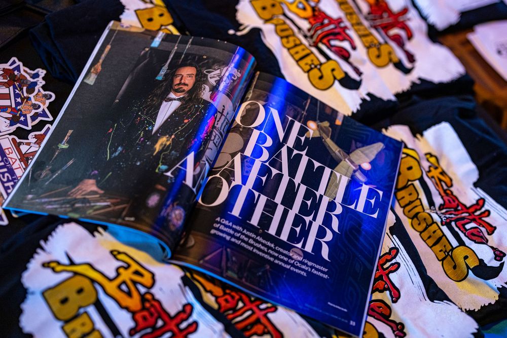 Magazine article titled One Battle After Another displayed among Battle of the Brushes merchandise.