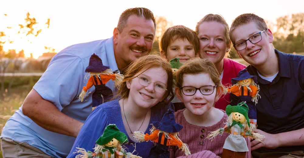 Group photo outdoors with sunflowers at sunset in warm golden light.