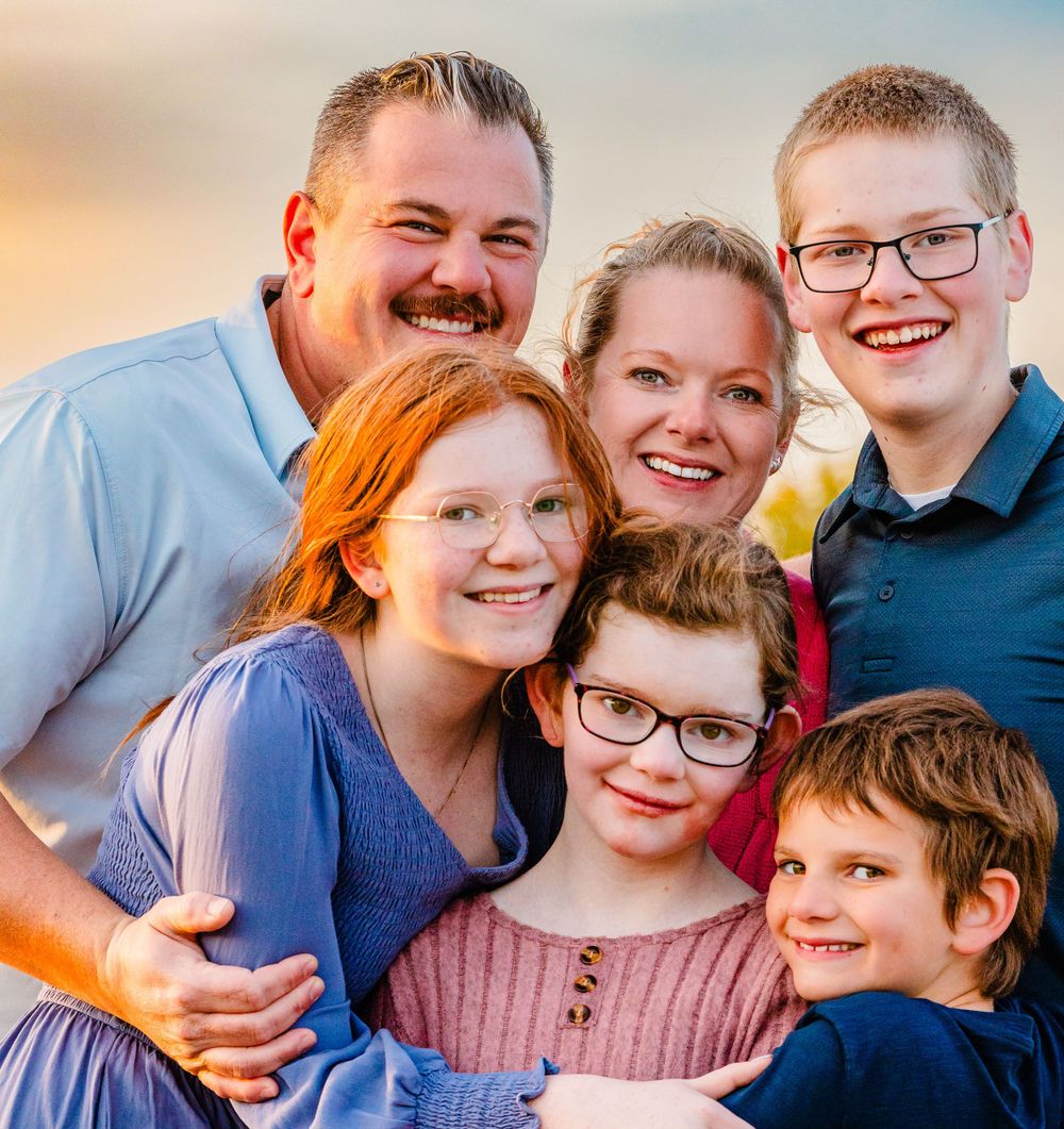 A happy family of six smiling together in a warm portrait photograph.