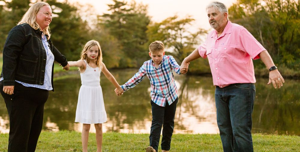 Family enjoying a walk together by a scenic pond at sunset during golden hour.
