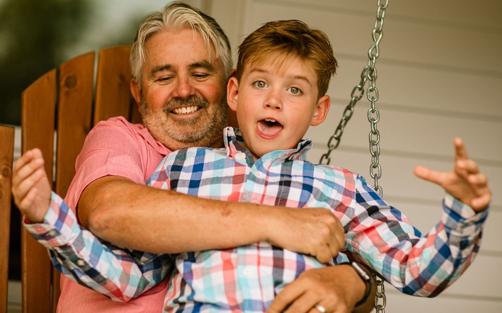 A playful moment shared between two people laughing and having fun while sitting on a porch swing together.